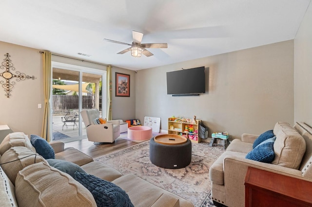 living room featuring wood finished floors, a ceiling fan, and visible vents
