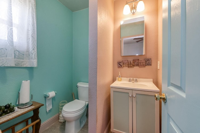 half bathroom featuring toilet, baseboards, and vanity