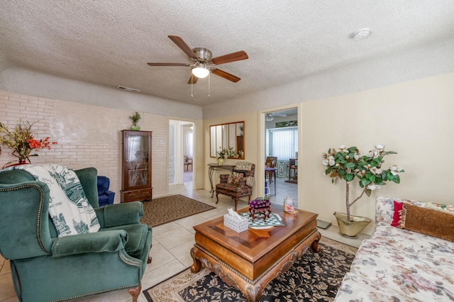 living area featuring ceiling fan, a textured ceiling, and light tile patterned floors