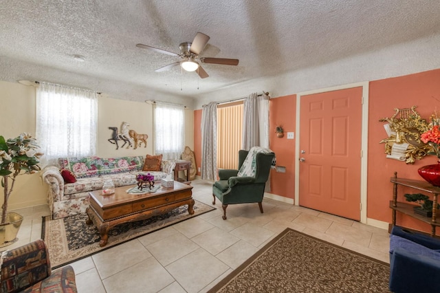 tiled living room with a ceiling fan, a textured ceiling, and baseboards