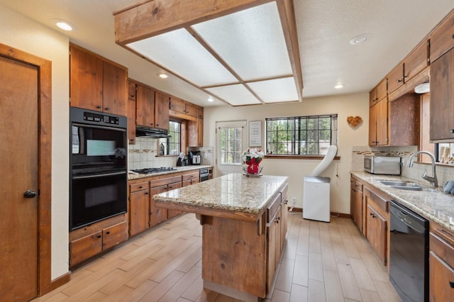 kitchen featuring brown cabinets, a sink, decorative backsplash, black appliances, and a kitchen island