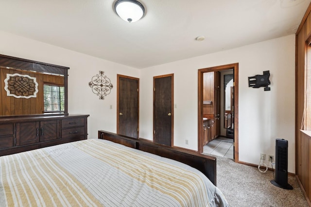 bedroom with connected bathroom, light colored carpet, and baseboards