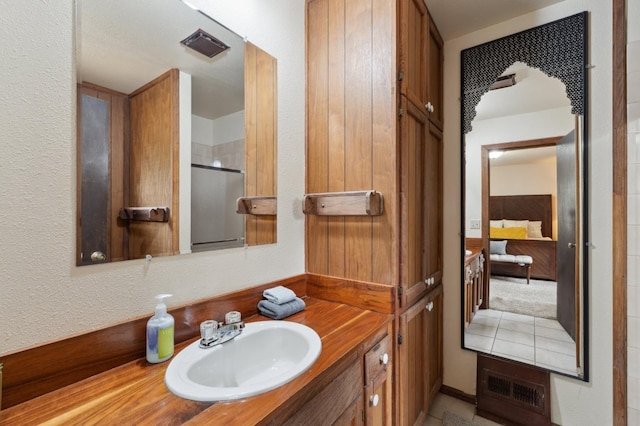 bathroom with a textured wall, ensuite bathroom, vanity, visible vents, and a stall shower