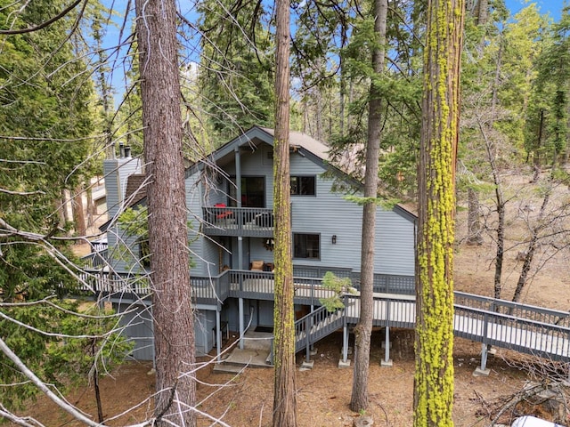 rear view of property with stairway, a balcony, and a wooden deck