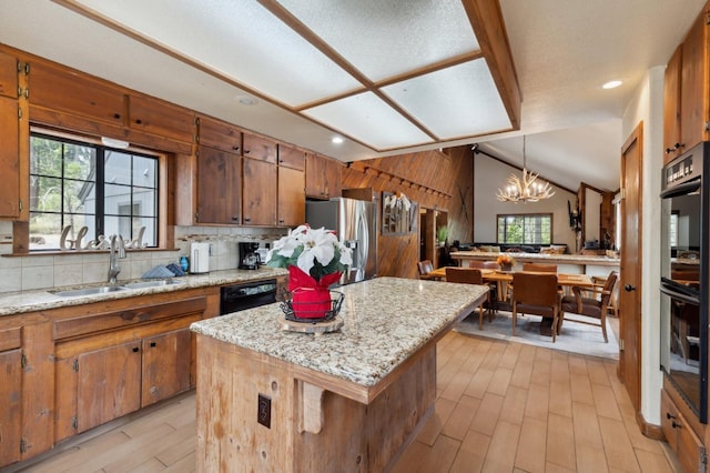 kitchen with brown cabinets, a sink, light wood-style floors, black appliances, and a notable chandelier