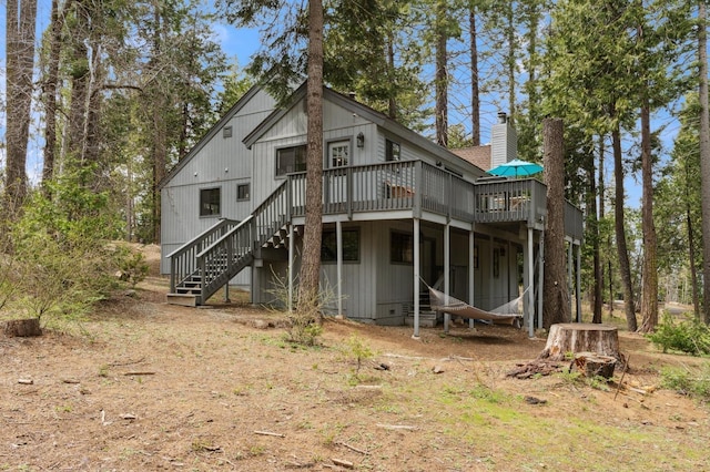 back of house featuring a deck, stairway, and a chimney
