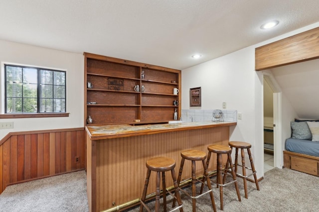 bar featuring wooden walls, bar area, recessed lighting, carpet, and wainscoting