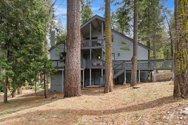 back of property with a deck, stairway, a chimney, and a balcony