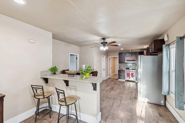555 S Sierra Vista Ave, Fresno, CA 93702 - kitchen with appliances with stainless steel finishes, light wood-type flooring, range hood, and a kitchen breakfast bar