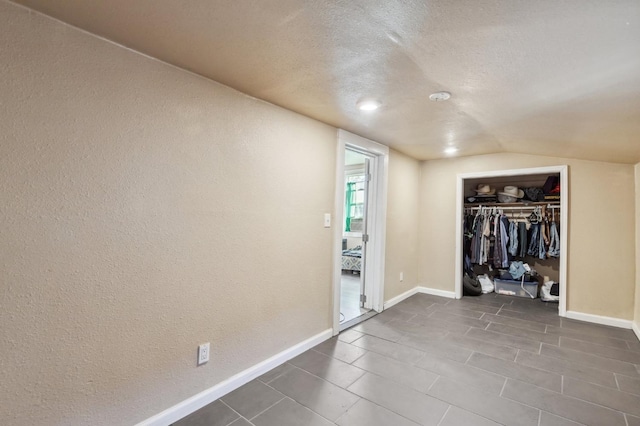 555 S Sierra Vista Ave, Fresno, CA 93702 - unfurnished bedroom featuring dark tile patterned flooring, a closet, vaulted ceiling, baseboards, and a textured ceiling