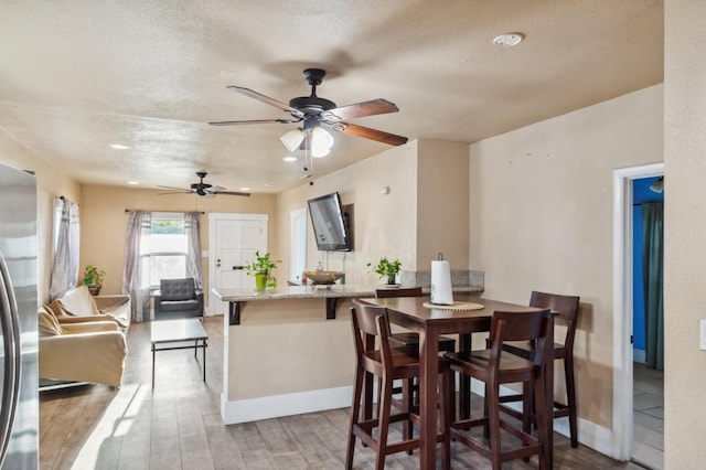 555 S Sierra Vista Ave, Fresno, CA 93702 - dining room featuring a textured ceiling, wood finished floors, a ceiling fan, and baseboards