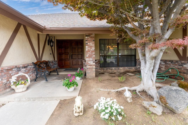 167 W Quincy Ave, Fresno, CA 93711 - doorway to property with a shingled roof, stucco siding, covered porch, and brick siding