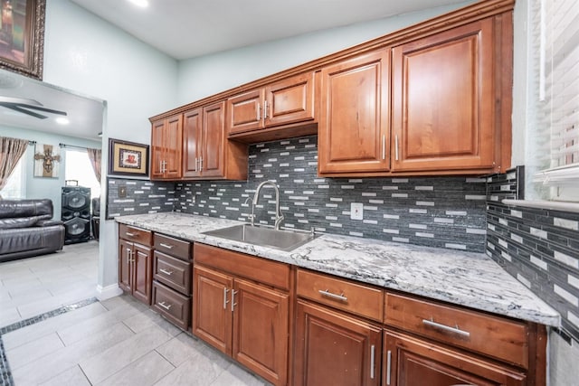 3336 N Lafayette Ave, Fresno, CA 93705 - kitchen featuring light stone counters, light tile patterned floors, brown cabinets, tasteful backsplash, and a sink