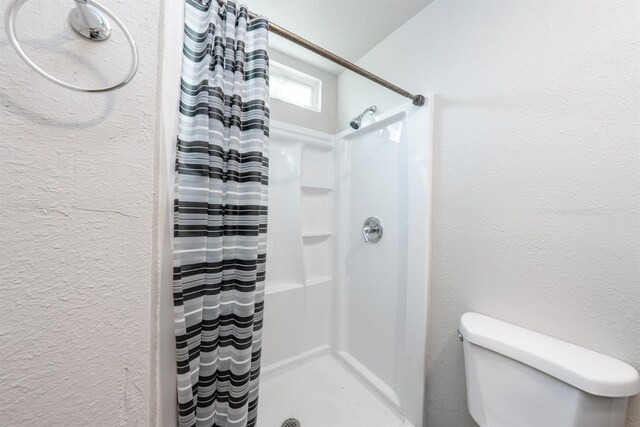3336 N Lafayette Ave, Fresno, CA 93705 - bathroom featuring toilet, a textured wall, and a shower stall