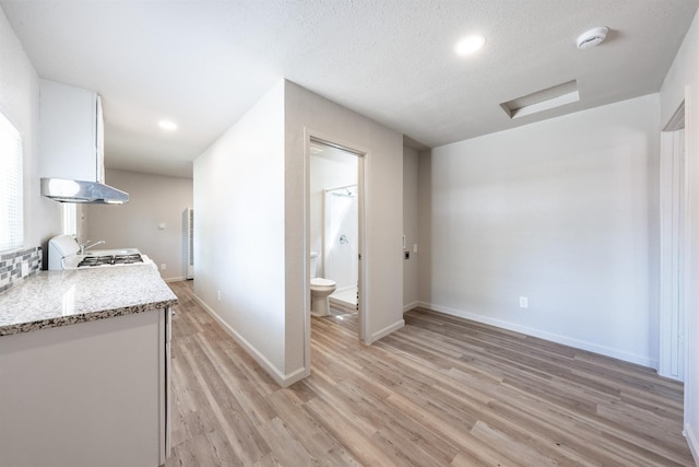3336 N Lafayette Ave, Fresno, CA 93705 - interior space featuring stove, baseboards, under cabinet range hood, white cabinetry, and light wood-type flooring