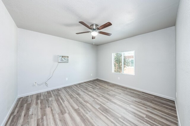 3336 N Lafayette Ave, Fresno, CA 93705 - unfurnished room with wood finished floors, ceiling fan, an AC wall unit, and baseboards
