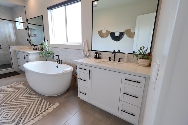 full bath with a freestanding tub, two vanities, a marble finish shower, and a sink