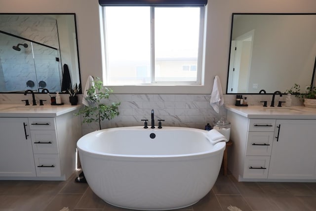 full bathroom featuring a freestanding tub, a shower stall, tile patterned flooring, and a sink