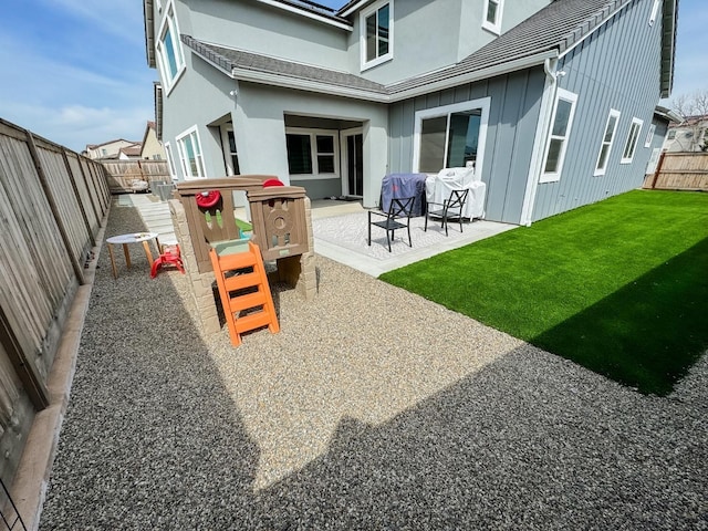 back of house featuring a lawn, board and batten siding, a fenced backyard, and a patio area