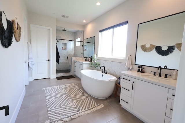 bathroom with visible vents, a stall shower, tile patterned floors, vanity, and a freestanding bath