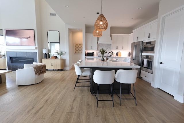 kitchen with a sink, light wood-style floors, visible vents, white cabinetry, and light countertops
