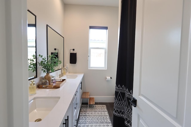 full bath with tile patterned floors, baseboards, double vanity, and a sink