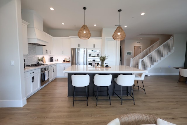 kitchen featuring stainless steel appliances, a kitchen breakfast bar, custom range hood, tasteful backsplash, and a center island