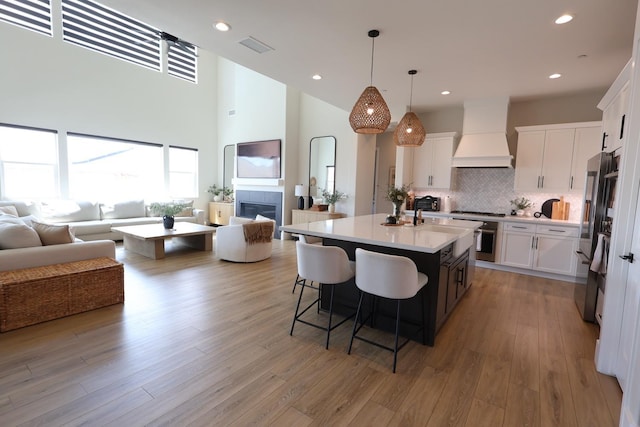 kitchen featuring custom exhaust hood, white cabinets, and open floor plan
