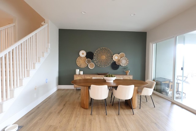 dining room with an accent wall, stairway, light wood-style floors, baseboards, and recessed lighting