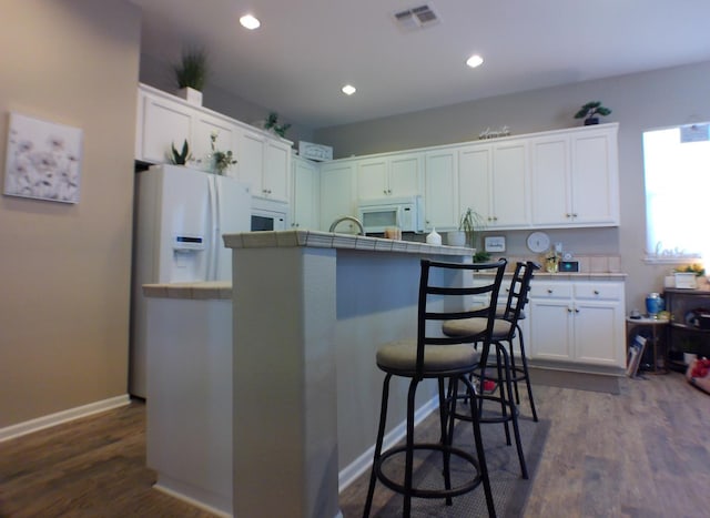 14335 Spyglass Cir, Chowchilla, CA 93610 - kitchen with tile counters, white microwave, white cabinets, a kitchen breakfast bar, and recessed lighting