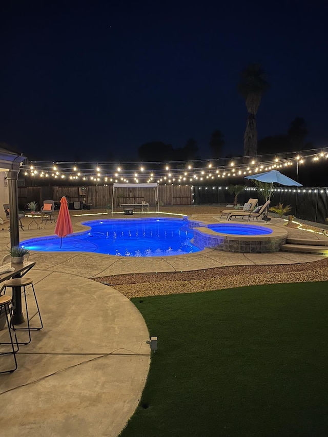 14335 Spyglass Cir, Chowchilla, CA 93610 - pool at night featuring a fenced backyard, a patio area, and a pool with connected hot tub