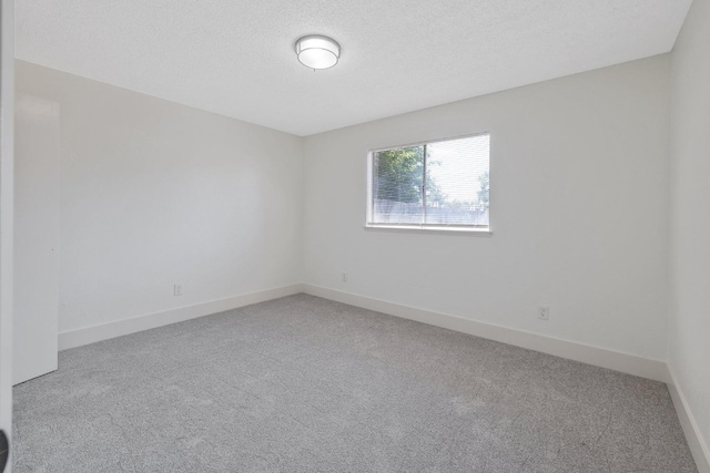 465 W Woods Ave, Tipton, CA 93272 - empty room featuring a textured ceiling, carpet floors, and baseboards