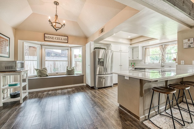 kitchen with a peninsula, light countertops, white cabinets, a tray ceiling, and appliances with stainless steel finishes