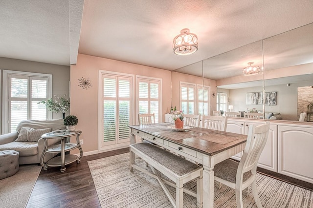 dining room featuring a textured ceiling, an inviting chandelier, dark wood-style floors, and baseboards