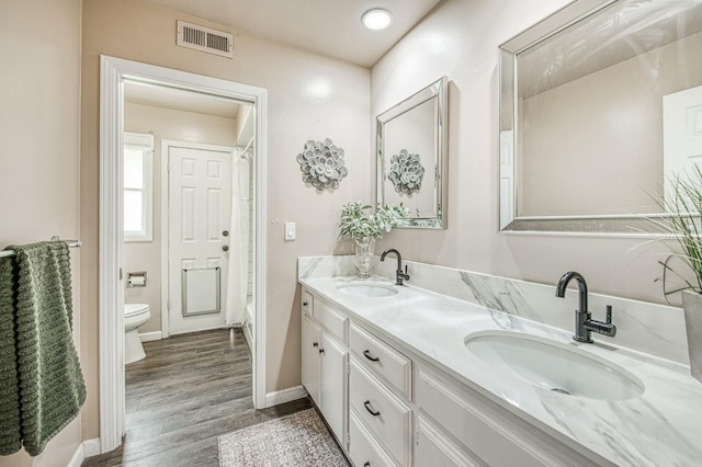 bathroom with a sink, toilet, double vanity, and visible vents
