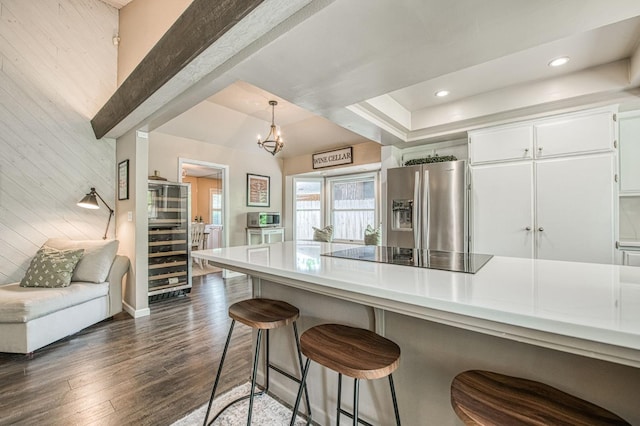 kitchen with stainless steel fridge with ice dispenser, a breakfast bar area, dark wood finished floors, and black electric stovetop