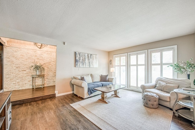 living room with baseboards, a textured ceiling, and wood finished floors