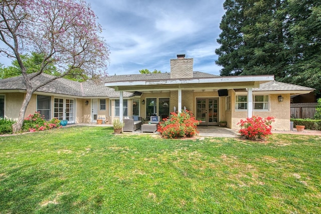back of house with a lawn, french doors, a chimney, and a patio