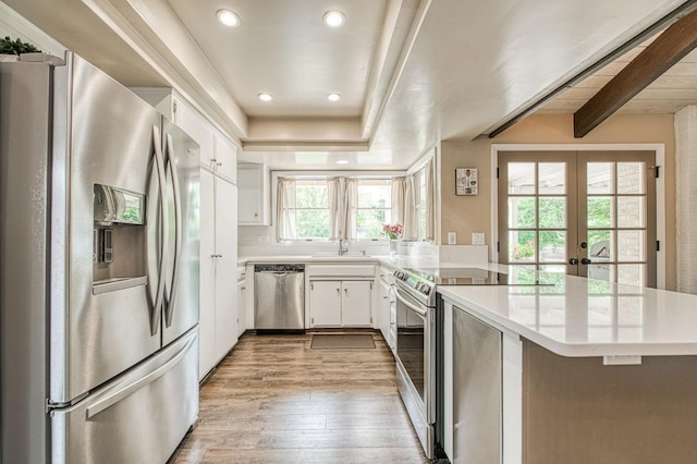 kitchen featuring french doors, appliances with stainless steel finishes, a sink, light countertops, and light wood-style floors