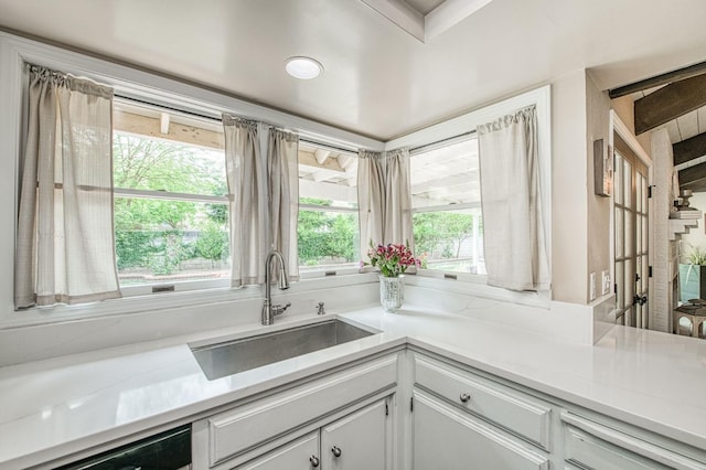 kitchen featuring light countertops, white cabinets, a sink, and dishwasher