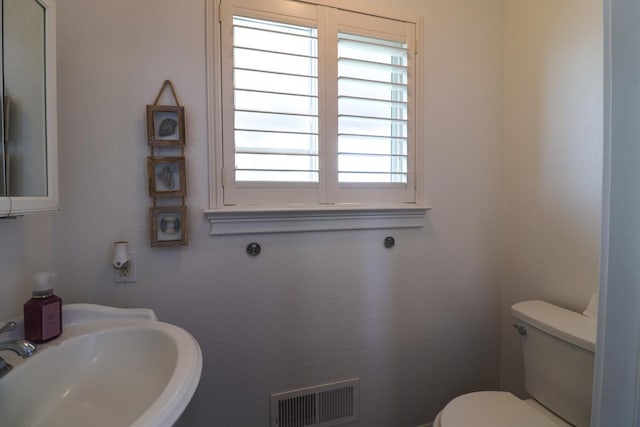 half bathroom featuring visible vents, a sink, and toilet