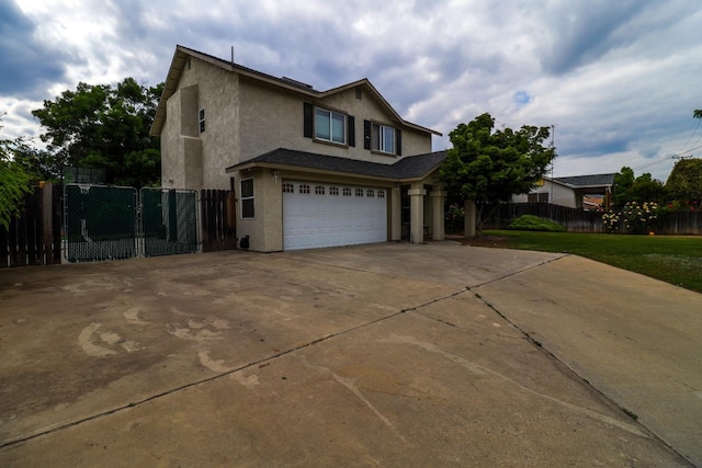 traditional-style home featuring a garage, fence, stucco siding, and driveway