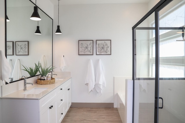 full bathroom with a sink, double vanity, a shower stall, wood finished floors, and a garden tub
