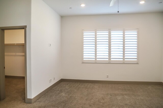 unfurnished bedroom with baseboards, a spacious closet, and carpet