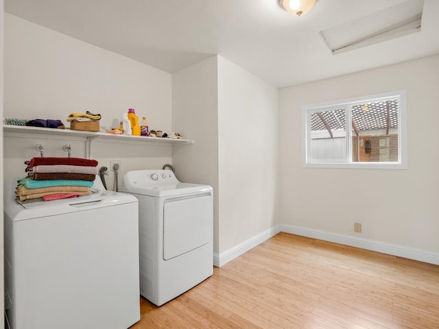 laundry area with laundry area, light wood-style floors, attic access, baseboards, and washing machine and clothes dryer