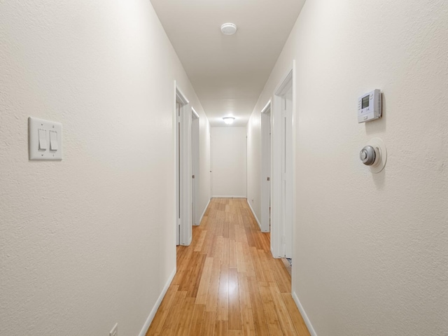 hall with baseboards and light wood-style floors
