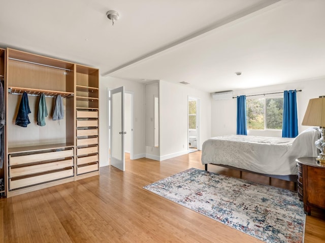 bedroom with baseboards, visible vents, wood finished floors, and a wall mounted air conditioner