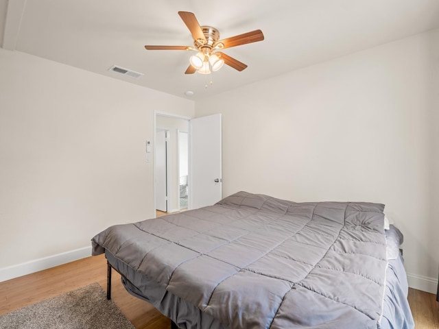 bedroom featuring ceiling fan, baseboards, visible vents, and wood finished floors