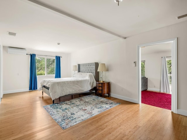 bedroom featuring visible vents, wood finished floors, and a wall mounted air conditioner