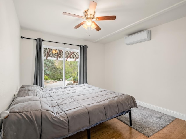 bedroom featuring baseboards, ceiling fan, a wall mounted air conditioner, and wood finished floors